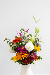 Colorful orange, white, purple flower bouquet in vase, white background, copy space, organic summer garden bouquet 