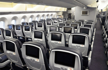 Commercial airplane seats with inflight entertainment displays/screens viewed from the rear