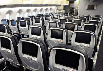 Commercial airplane seats with inflight entertainment displays/screens viewed from the rear