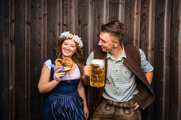 Junge Frau und mann mit Bierkrug und Brezel auf einem Holzhintergrund .Oktoberfest-Konzept 