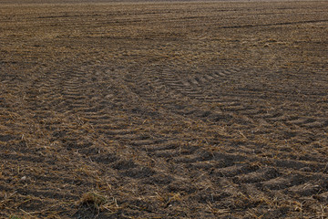 Close up top view of tire pattern from heavy tractor wheel mark trail on agricultural soil.