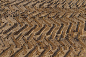 Close up top view of tire pattern from heavy tractor wheel mark trail on agricultural soil.