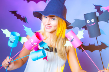 The girl celebrates Halloween. Girl holds in the hands of vampires from paper. A woman in a hat decorates the house for Halloween. Funny colored paper vampires.