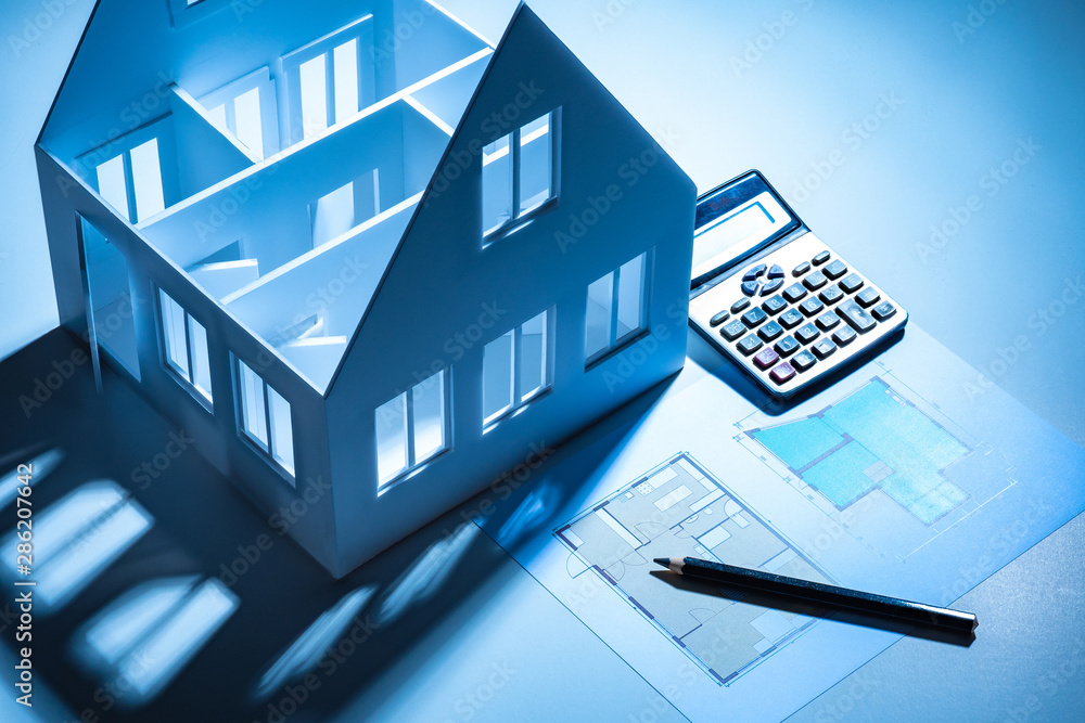 Poster the layout of the house, a calculator and a building scheme on white table. the designer is developi
