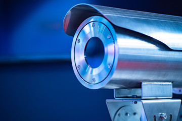 Surveillance camera at the factory. Secure the camera on a blue background. Security at the...