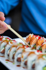 caucasian man eating sushi, hand eating sushi roll with chopsticks, japanese food, eating at a japanese restaurant