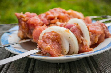 Raw pork meat for shish kebab on skewers. Preparing for a picnic . Soft focus, selected focus.