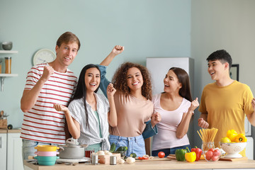 Happy friends cooking together in kitchen