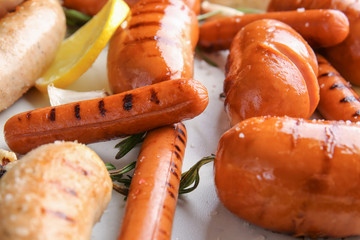 Assortment of tasty grilled sausages on light background, closeup