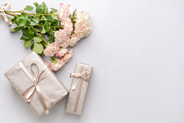 Gift boxes and beautiful flowers on light background