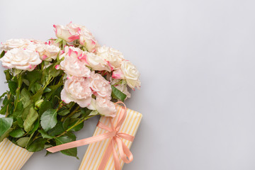 Gift box and beautiful flowers on light background