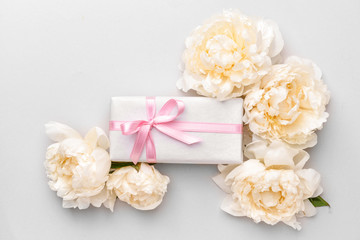 Obraz na płótnie Canvas Gift box and beautiful flowers on light background