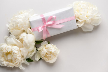 Gift box and beautiful flowers on light background