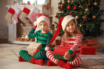 Cute little children with Christmas gifts at home