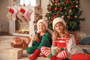 Obraz na płótnie Canvas Cute little children drinking hot chocolate on Christmas eve at home