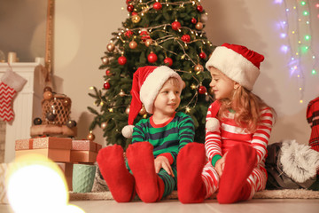 Cute little children in Santa Claus hats on Christmas eve at home