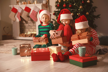 Fototapeta na wymiar Cute little children opening Christmas gifts at home