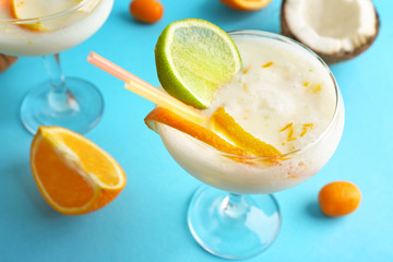 Glass of tasty Pina Colada cocktail and fruits on color background