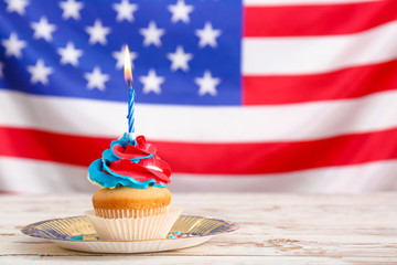 Tasty patriotic cupcake on table against USA flag