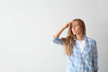 Beautiful young woman looking faraway on light background