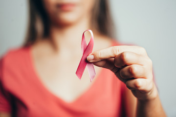 Healthcare and medicine concept - woman holding pink breast cancer awareness ribbon