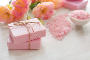Soap, flowers and sea salt on light background