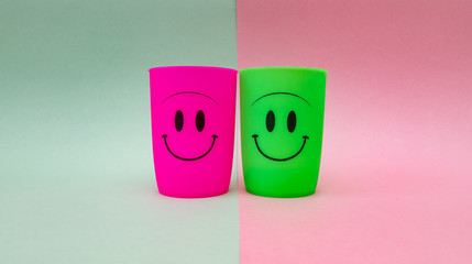 Pink and green glasses with happy smiling faces, isolated on pink and green background