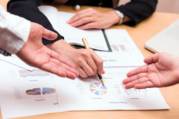 The team's hand point to financial reports during the meeting. To consult your company's sales. business document help discussion plan.