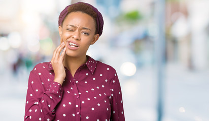 Beautiful young african american woman wearing head scarf over isolated background touching mouth...