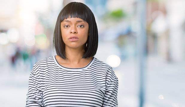 Beautiful young african american woman wearing stripes sweater over isolated background Relaxed with serious expression on face. Simple and natural looking at the camera.