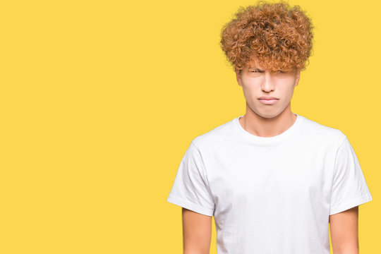 Young handsome man with afro hair wearing casual white t-shirt skeptic and nervous, frowning upset because of problem. Negative person.
