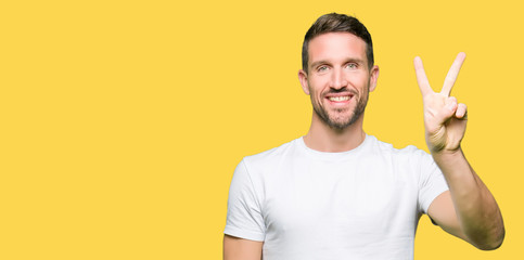 Fototapeta premium Handsome man wearing casual white t-shirt showing and pointing up with fingers number two while smiling confident and happy.