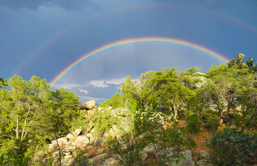 A Double rainbow shines brightly over the high desert landscape.