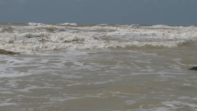 A row of small waves quickly scuttling on a beach.