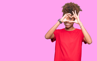 Beautiful young african american woman over isolated background Doing heart shape with hand and fingers smiling looking through sign