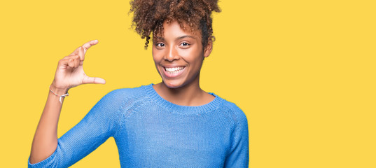 Beautiful young african american woman over isolated background smiling and confident gesturing with hand doing size sign with fingers while looking and the camera. Measure concept.