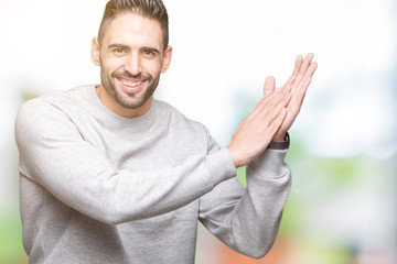 Young handsome man wearing sweatshirt over isolated background Clapping and applauding happy and joyful, smiling proud hands together