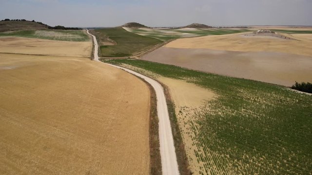 Aerial view of pilgrims walking on path near Hontanas, Spanish town along Camino de Santiago or Way of St James. People on road in Spain seen from drone flying in sky