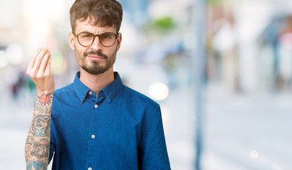 Young handsome man wearing glasses over isolated background Doing Italian gesture with hand and fingers confident expression