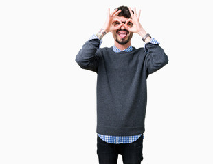 Fototapeta premium Young handsome smart man wearing glasses over isolated background doing ok gesture like binoculars sticking tongue out, eyes looking through fingers. Crazy expression.