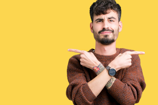 Young handsome man wearing winter sweater over isolated background Pointing to both sides with fingers, different direction disagree