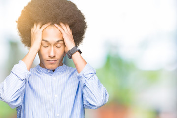 Young african american man with afro hair suffering from headache desperate and stressed because pain and migraine. Hands on head.