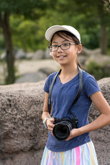 Young little photographer with a digital camera taking photo outdoors