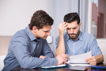Fototapeta premium Two serious males with documents at table