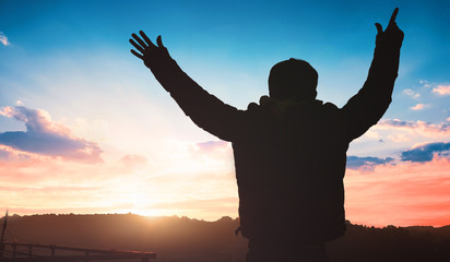 Human Rights Day concept: a man raising his hands over sunset background