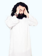 Man wearing Jesus Christ costume with hand on head for pain in head because stress. Suffering migraine.