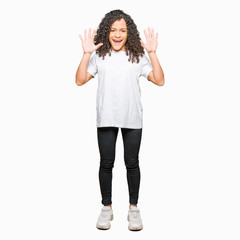 Obraz premium Young beautiful woman with curly hair wearing white t-shirt showing and pointing up with fingers number ten while smiling confident and happy.