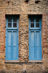 old blue windows with shutters on dilapidated walls