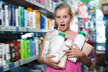 Happy girl holding shampoo and shower gel