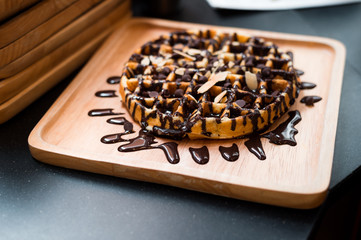 waffles with chocolate sauce on wooden plate